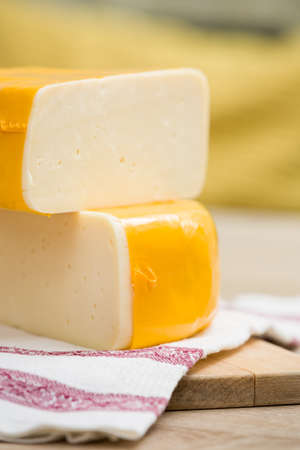 Two big organic cheese heads in yellow vacuum package laying on top of each other in the farm kitchen.  Food conceptの写真素材