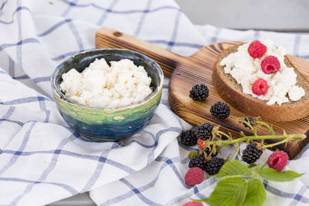 Organic Farming Cottage cheese in a green bowl, slice of whole wheat bread with Homemade Ricotta cheese served with raspberries and blackberries on wooden board  on linen fabricの写真素材