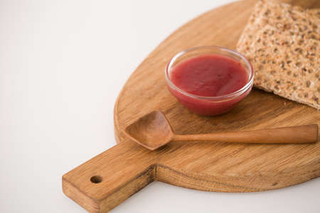 Top view on wooden board with organic wholegrain crisps with strawberry jam on kitchen table. Healthy Breakfast or snack. Healthy food and eating.の写真素材
