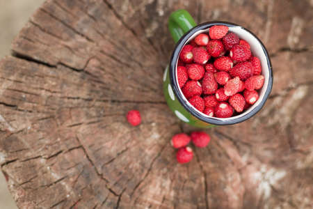 Top view on a metal retro cup full of fresh organic garden strawberries on old wood. Healthy snack and summer food.の写真素材