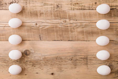 Top view on white eggs on a wooden background. Easter festive background. Flat lay.の写真素材