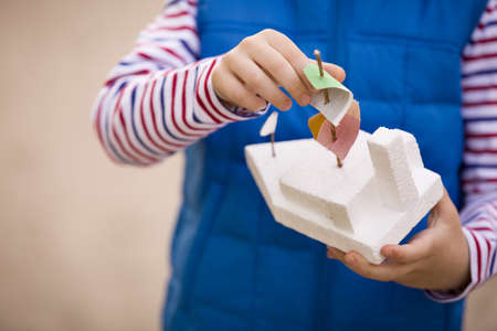 Closeup of child's hands holding handmade toy boat. Child with toy ship outdoors.
