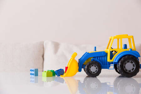 Closeup of children toy tractor with colorful plastic bricks or details on white background. Baby's toys on the table isolated.の写真素材