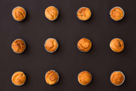 Top view on homemade vanilla muffins places in rows on black background. Healthy snack.の写真素材