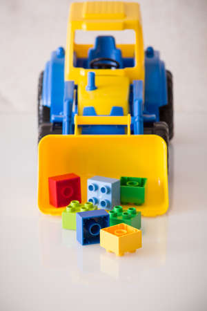 Closeup of children toy tractor with colorful plastic bricks or details on white background.の写真素材