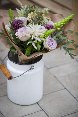 Closeup of white metal bucket full of beautiful flowers. Flowers in vase on concrete background. Summer or spring. Outdoorの写真素材