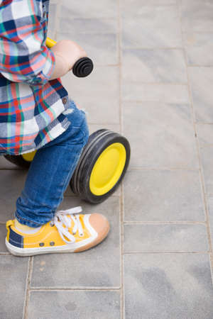 Small toddler boy riding his toy bicycle on street concrete. Child learning to ride a bike.の写真素材