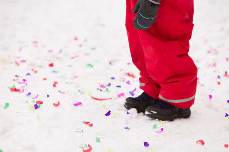 Child standing on snow with confetti. Celebration, Christmas and winter concept.