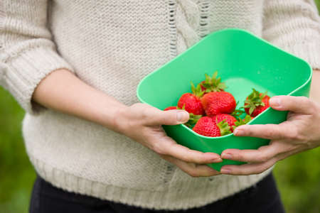 Closeup of woman's hands holding bowl with organic garden summer strawberry berries. Healthy lifestyle and healthy eating. Vegetarian snack.Fruit and berries.の写真素材