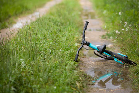 Closeup of children small bicycle on a countryside road after rain. Nature background.の写真素材