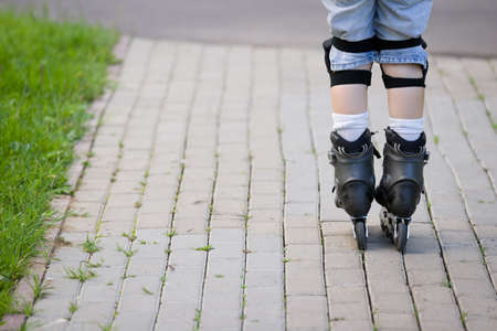 Closeup view of black roller skates or rollerblading. Roller skate legs of a child in the park. Boy's legs in roller blades.の写真素材