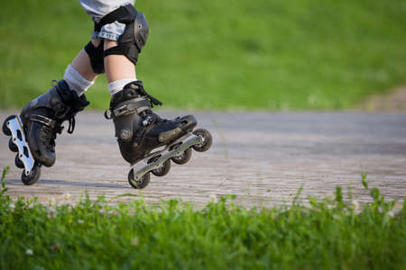 Closeup view of black roller skates or rollerblading. Roller skate legs of a child in the park. Boy's legs in roller blades.の写真素材
