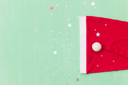 Top view on Santa's hats on retro wooden turquoise background with shiny stars. Christmas, winter...
