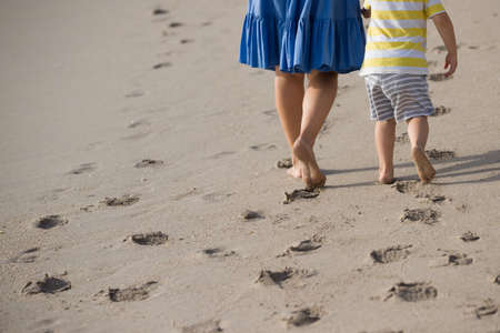 Vacation concept. Close up of female and child  legs walking by the beach. Mother and son by the sea.の写真素材