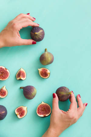 Top view on girl's hands holding fresh organic figs on turquoise table background.の写真素材