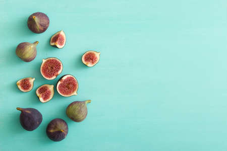 Top view on sliced and full fresh figs on turquoise wooden table or background. Healthy snack and food.の写真素材