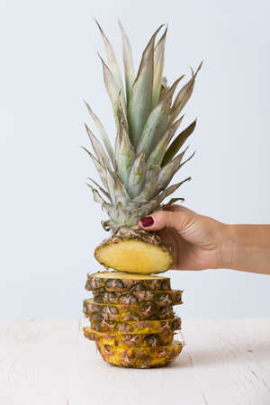 Girl's hand holding head of fresh sliced pineapple.の写真素材