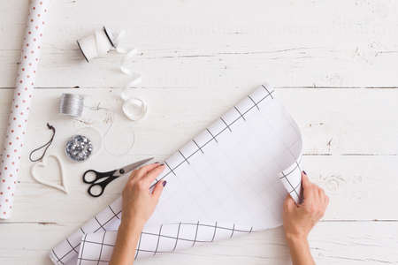 Top view on girl's hands wrapping Christmas or birthday gift in nice black and white paper....