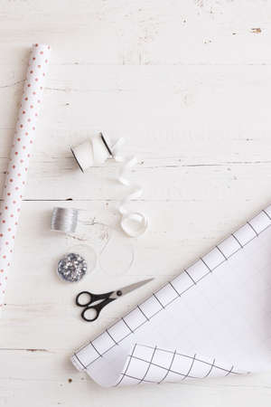 Top view on gift paper and decorations on white wooden background. Preparing gifts for birthday or...