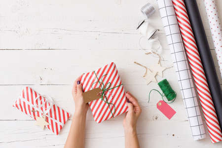 Top view on girl's hands wrapping Christmas or birthday gift. Preparing present for celebrationの写真素材