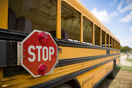 A red stop sign with lights on the side of an old yellow school bus. Back to schoolの写真素材