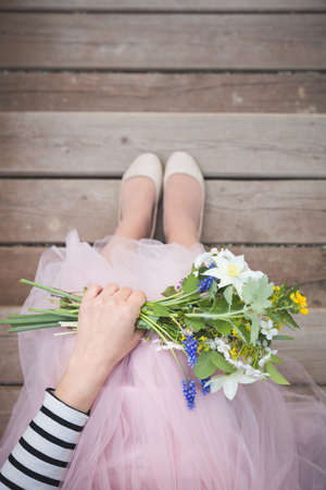 Top view on woman holding beautiful bunch of spring flowers. Girl with bouquet of daffodils, apple tree flowers and other garden flowers. Summer and spring concept. Selective focus.の写真素材