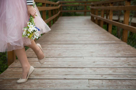 woman holding beautiful bunch of spring flowers. Girl with bouquet of daffodils, apple tree flowers and other garden flowers. Summer and spring concept.  Closeup of legs.の写真素材