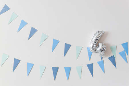 Blue color flags garland with balloon in shape of number 4 on white wall. Party banner.