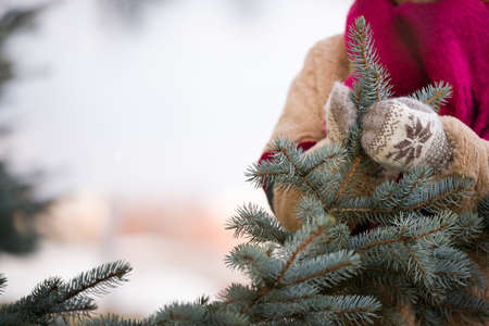 Young woman decorating Christmas tree outdoors. Closeup of hands in mittens with Christmas decor. Christmas and winter concept.の写真素材
