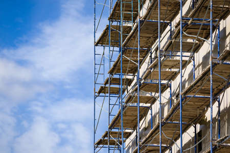 Scaffolding near a new house under construction as the temporary support building structure during construction against the blue sky.の写真素材