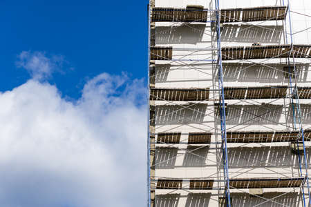 Scaffolding near a new house under construction as the temporary support building structure during construction against the blue sky.の写真素材