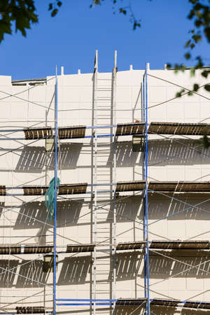 Scaffolding near a new house under construction as the temporary support building structure during construction against the blue sky.の写真素材