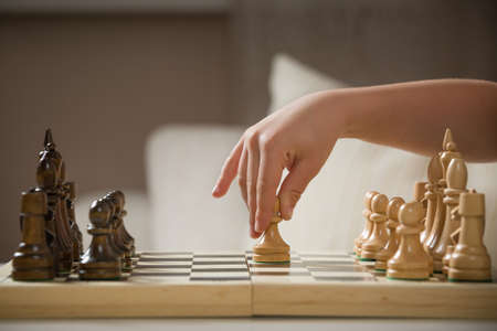 Child's hand holding chess figure while playing chess. Little clever child playing chess at home. Education concept.の写真素材