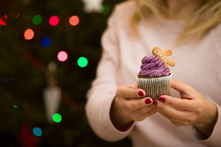 Closeup of delicious cupcake with gingerbread man in hands of a young woman. Christmas and holiday seasonの写真素材