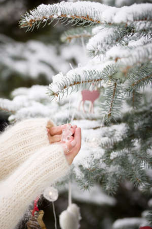 Closeup of girl's hands decorating Christmas tree with crystal star decor. Winter, holidays season and Christmas concept. Traditional celebration.の写真素材