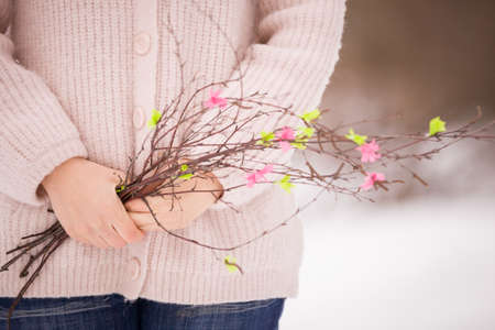 Cute girl in a winter park on a cold day with a sprig of a tree. The girl enjoys a walk in nature. Lifestyle conceptの写真素材