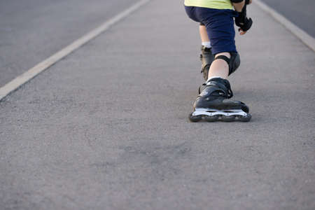 Closeup of black roller skates or rollerblading. Roller skate legs of a child in the park. Boy's legs in roller blades.の写真素材