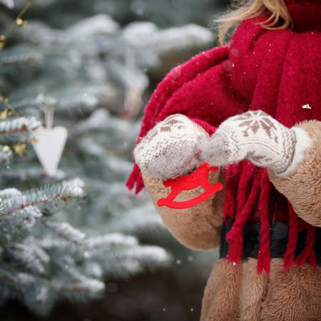 Closeup of a young woman holding in her hands decorations for a Christmas fir in the shape of a horse. Decorated Christmas tree. New Year and Christmas conceptの写真素材