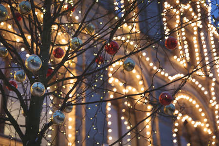 Multicolored decorations on trees and festive illumination on the streets of the city. New Year and...