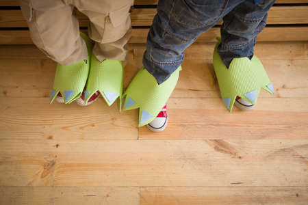 Top view on Children's feet decorated under the feet of an animal, a dinosaur. Idea for kids celebration. Festive conceptの写真素材