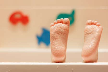 The legs of the baby are wrinkled from a long stay in the water against the background of a wall...