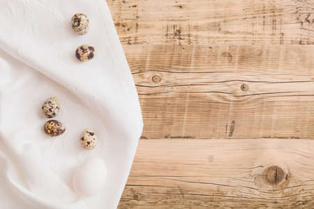 Top view on fresh eggs lying on white beautiful cloth on a natural wooden table. Easter festive...