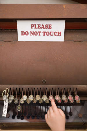 The hand of the child reaches for the buttons of the vintage cash register. The inscription on the...