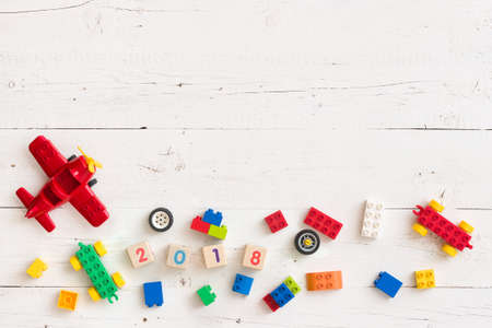 Multi-colored cubes, bricks and toys from plastic. Wooden cubes with numbers 2018 on a white wooden table. Early learning. Educational toysの写真素材