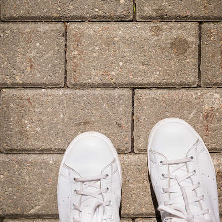 Top view on white sneakers standing on the pavement. Paved path in the city park. Copy space for text. Crosswalk, safetyの写真素材