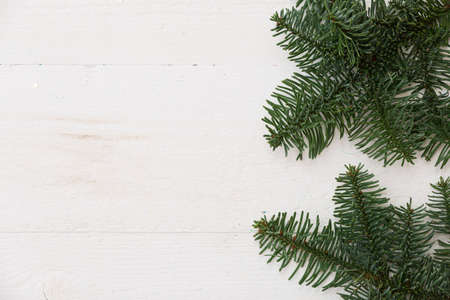 Top view of the fir branches lying on a white wooden table. Christmas mood. Copy space. New Year or...