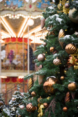 Christmas holiday decorations in the center of Moscow in the evening. Christmas toys hang on the branches of spruce, and garlands sparkle with different colors against the background of a carouselの写真素材