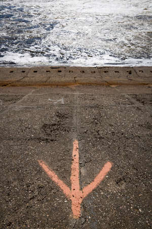 Dam on the river in case of rising water level with a drawn arrow. Concrete slabs leaving under...