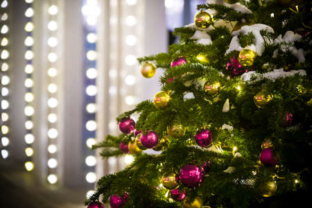 Evergreen spruce with toys and sparkling garlands, covered with snow against the background of the night sky and blurry garlands. New Year decorations in the center of Moscow. Christmas Holidays. Selective focusの写真素材