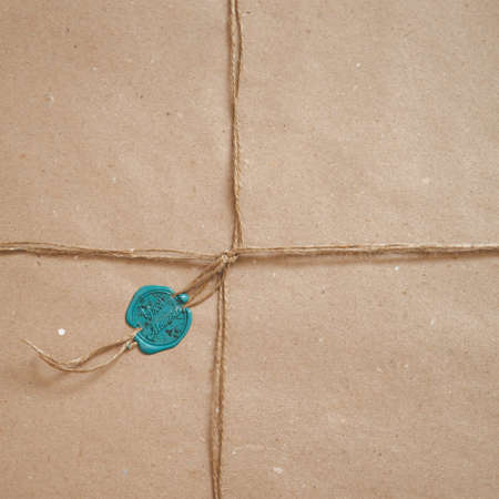 Top view of a parcel wrapped in paper, tied with a cord and sealed with a wax stamp. Stamp with the inscription Good Moments. Gift wrapped in paper.の写真素材